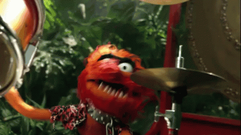 A Muppet Playing A Drum Set With A Jungle Background GIF