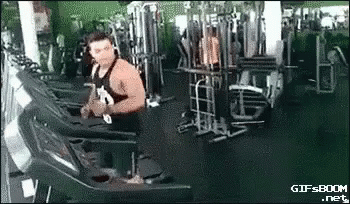 A Muscular Man Is Running On A Treadmill In A Gym . GIF