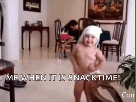 a naked baby is dancing in a living room with the words `` me when it is snacktime '' .