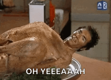 A Naked Man Is Laying On Top Of A Turkey On A Table . GIF
