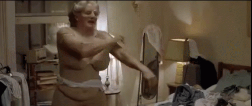 A Naked Woman Is Standing In A Messy Room With A Mirror . GIF