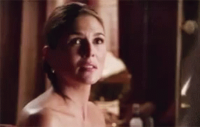 A Naked Woman Is Standing In Front Of A Mirror Looking At Herself . GIF