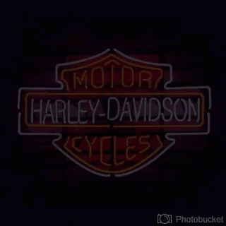 A Neon Sign For Harley Davidson Cycles On A Red Background GIF