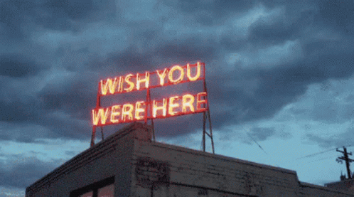 A Neon Sign On Top Of A Building Says " Wish You Were Here " GIF