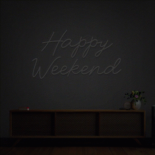 A Neon Sign That Says Happy Weekend Is Lit Up In A Dark Room GIF