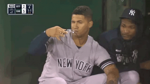 A New York Yankees Baseball Player Is Kneeling Down In The Dugout During A Game . GIF