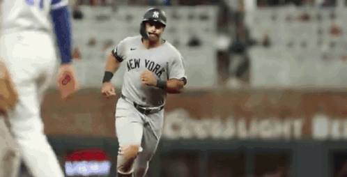A New York Yankees Baseball Player Is Running On The Field During A Baseball Game . GIF