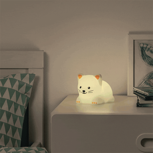 a nightstand with a cat shaped lamp on it