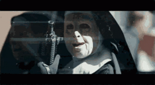 A Nun Is Holding A Gun In Her Hand In A Dark Room . GIF