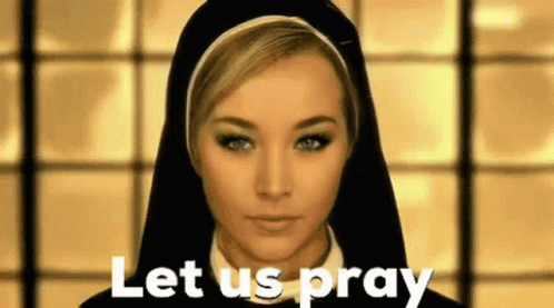 A Nun Is Standing In Front Of A Window And Says Let Us Pray . GIF