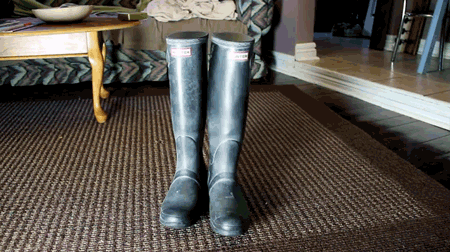 A Pair Of Black Hunter Boots Are On A Rug GIF