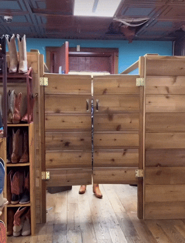 a pair of cowboy boots are hanging on a shelf next to a wooden door