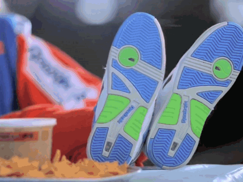 A Pair Of Reebok Shoes Are Laying On A Table Next To A Plate Of French Fries GIF