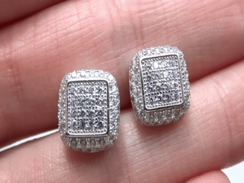 A Pair Of Square Shaped Stud Earrings Are Being Held In Someone 'S Hand GIF