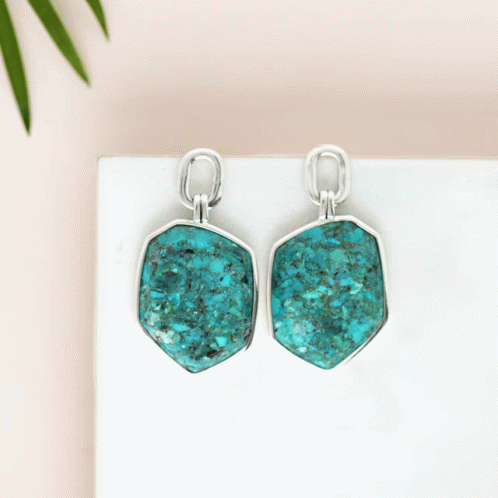A Pair Of Turquoise Earrings Are Sitting On A Table GIF