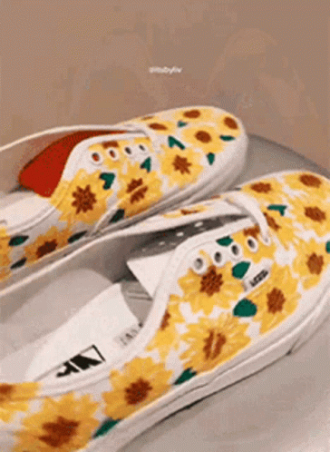 A Pair Of Yellow And White Vans Shoes With Sunflowers Painted On Them . GIF