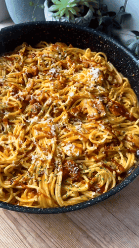 A Pan Filled With Noodles And Sauce On A Wooden Table GIF