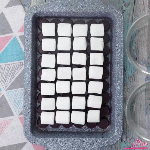 A Pan Filled With Squares Of Marshmallows On Top Of Chocolate Covered Oreos GIF