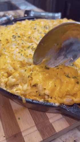 A Pan Of Macaroni And Cheese With A Spoon In It GIF