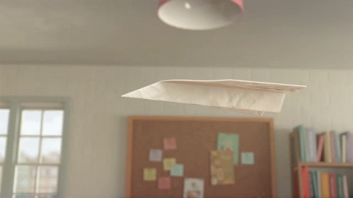 A Paper Airplane Is Flying In Front Of A Bulletin Board That Says " The Aviator " On It GIF