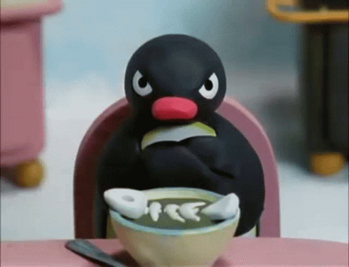 A Penguin Is Sitting At A Table With A Bowl Of Soup In Front Of Him GIF
