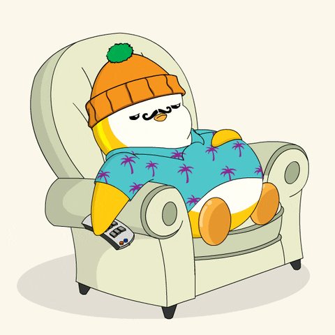 A Penguin Is Sitting In A Chair With A Remote Control GIF