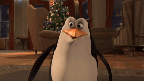 A Penguin Is Standing In Front Of A Christmas Tree In A Living Room GIF