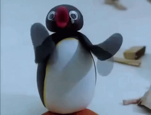 A Penguin Made Out Of Clay Is Standing On Top Of A Piece Of Wood . GIF