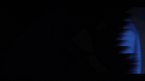 A Person Covering Their Face With Their Hand While A Red Light Shines On Them GIF
