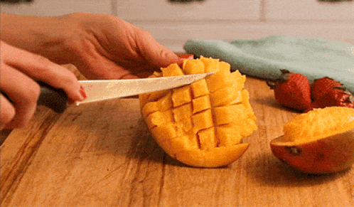 A Person Cutting A Mango On A Cutting Board GIF