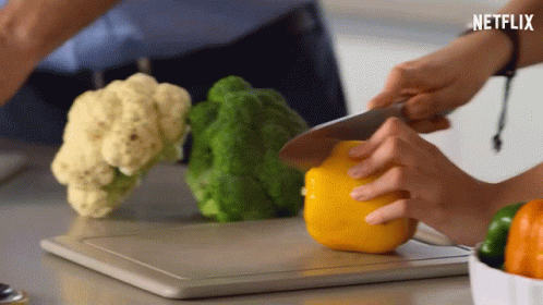 A Person Cutting Vegetables On A Cutting Board With Netflix Written On The Bottom GIF