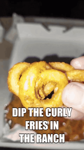 a person dipping curly fries in ranch sauce