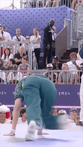 A Person Doing A Handstand In Front Of A Crowd With The Year 2024 On The Wall GIF