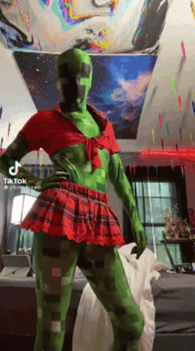 A Person Dressed As A Creeper In A Red And Green Outfit GIF