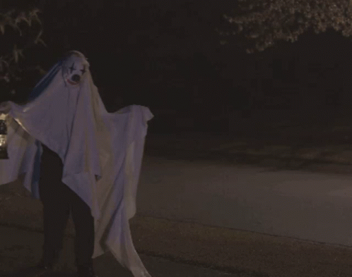 A Person Dressed As A Ghost Holding A Lantern With The Word Boo Written On The Bottom GIF