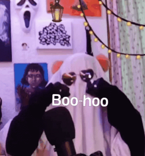 A Person Dressed As A Ghost Is Sitting In Front Of A Microphone And Holding Glasses . GIF