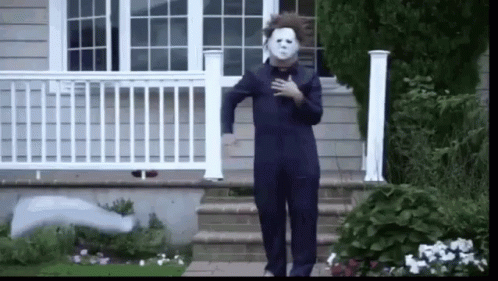 a person dressed as michael myers is walking down a set of stairs .