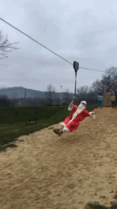 A Person Dressed As Santa Claus Is Riding A Zip Line GIF
