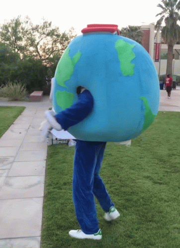 A Person Dressed In A Globe Costume Walking On A Grassy Sidewalk GIF
