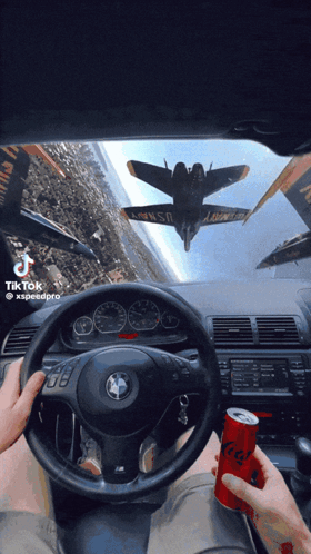 A Person Driving A Car With A Can Of Soda In Front Of Them GIF