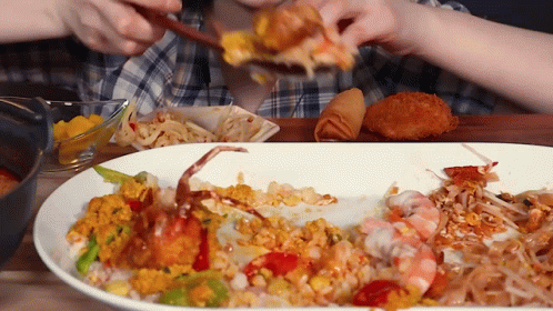 A Person Eating A Plate Of Food With A Crab On It GIF