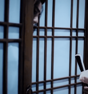 A Person Holding A Cell Phone Behind Bars GIF