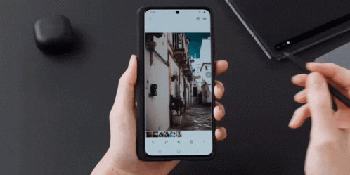 A Person Holding A Cell Phone With A Picture Of A Street On It GIF