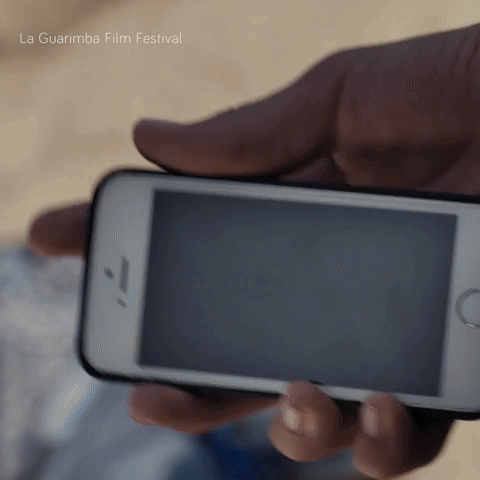 A Person Holding A Cell Phone With La Guarimba Film Festival Written In The Background GIF