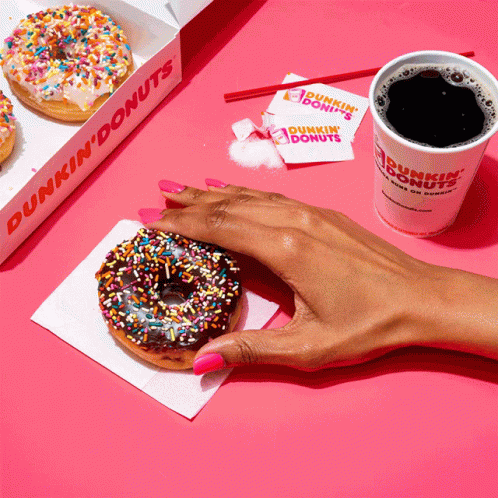 A Person Holding A Donut Next To A Dunkin Donuts Cup GIF