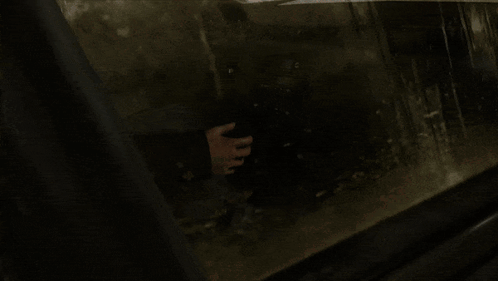 A Person Holding A Gun In A Dark Room With A Blurred Background GIF