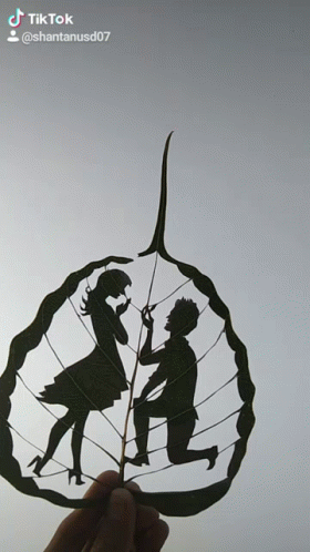 A Person Holding A Leaf With A Silhouette Of A Man And Woman On It GIF