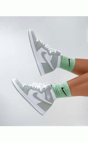 A Person Holding A Pair Of Green And White Nike Sneakers GIF