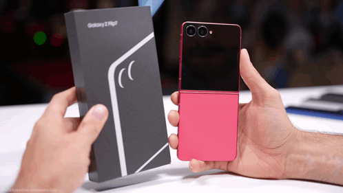 A Person Holding A Pink Flip Phone Next To A Box That Says Galaxy GIF