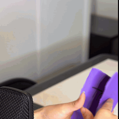 A Person Holding A Purple Object In Front Of A Black Microphone GIF